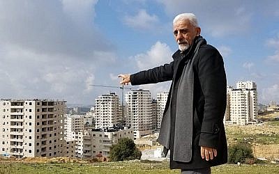 Munir Zughayer, un activiste qui dirige un comité qui se plaint souvent de la situation des services à Kafr Aqab auprès de la municipalité de Jérusalem, pointe du doigt un certain nombre de bâtiments construits en violation de la réglementation le 20 février 2019. (Crédit : Adam Rasgon / Times of Israël) Munir Zughayer, un activiste qui dirige un comité qui se plaint souvent de la situation des services à Kafr Aqab auprès de la municipalité de Jérusalem, pointe du doigt un certain nombre de bâtiments construits en violation de la réglementation le 20 février 2019. (Crédit : Adam Rasgon / Times of Israël)