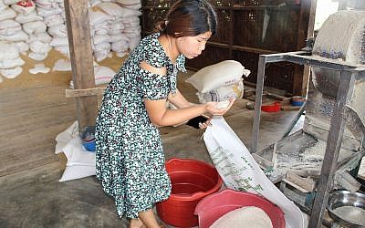 Zenan Sumlut examine du riz dans un moulin à riz qu'elle gère, à Kachin, en Birmanie. (Crédit : Emily Fishbein/Times of Israel)