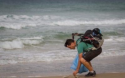 Le blogger israélien Gil Drori ramasse une sac plastique sur la plage de Beit Yanai le 23 novembre 2018, lors de son voyage de 9 jours pour sensibiliser sur le effets néfastes de la pollution d'objets plastiques jetables sur la mer Méditerranée. (Meir Vaknin/Flash90)
