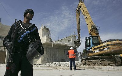 Photo d'illustration : Un agent de police israélien se tient près d'une pelleteuse lors de la démolition d'une maison palestinienne dans la banlieue de Sur Baher, à Jérusalem-Est, le 7 avril 2009 (Crédit : Kobi Gideon / FLASH90)