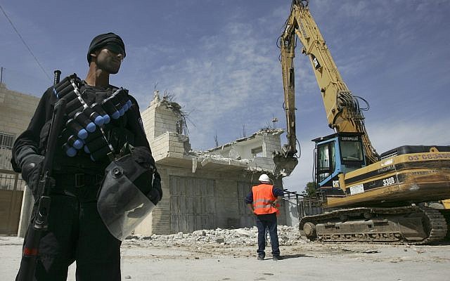 Photo d'illustration : Un agent de police israélien se tient près d'une pelleteuse lors de la démolition d'une maison palestinienne dans la banlieue de Sur Baher, à Jérusalem-Est, le 7 avril 2009 (Crédit : Kobi Gideon / FLASH90)