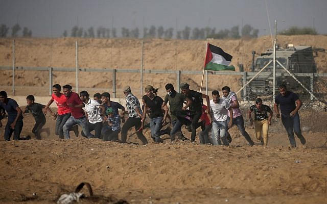 Des manifestants palestiniens fuient la clôture pendant les manifestations le long de la frontière avec Israël, à l'est de Khan Younis, dans le sud de Gaza, le 12 juillet 2019 (Crédit : Mahmud Hams/AFP) Des manifestants palestiniens fuient la clôture pendant les manifestations le long de la frontière avec Israël, à l'est de Khan Younis, dans le sud de Gaza, le 12 juillet 2019 (Crédit : Mahmud Hams/AFP)