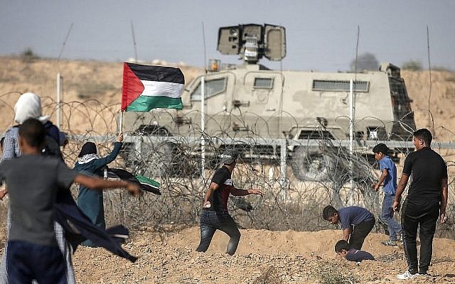 Des manifestants palestiniens jettent des pierres en direction des forces de sécurité israéliennes au cours des manifestations le long de la frontière avec Israël, à l'est de Khan Younès, dans le sud de la bande de Gaza, le 12 juillet 2019. (Crédit : MAHMUD HAMS / AFP) Des manifestants palestiniens jettent des pierres en direction des forces de sécurité israéliennes au cours des manifestations le long de la frontière avec Israël, à l'est de Khan Younès, dans le sud de la bande de Gaza, le 12 juillet 2019. (Crédit : MAHMUD HAMS / AFP)