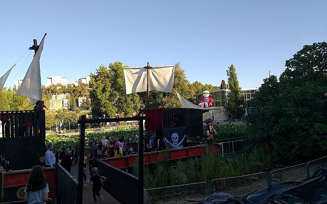 Les enfants jouent sur un bateau pirate avec des figurines Playmobil grandeur nature au Jardin botanique de Jérusalem, le 15 juillet 2019 (Crédit : Joshua Davidovich/Times of Israel)