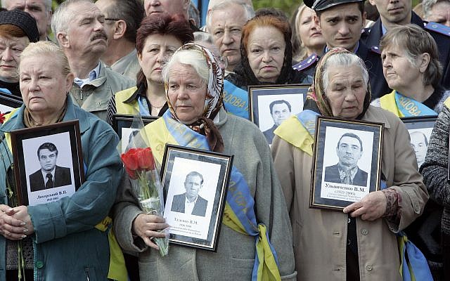 Les veuves des victimes de Tchernobyl arborent des portraits de leurs maris décédés à la suite des opérations de nettoyage de l'explosion nucléaire de Tchernobyl en 1986, au monument érigé à la mémoire des victimes, à Kiev, capitale de l'Ukraine, le 26 avril 2008. (AP Photo/Efrem Lukatsky)