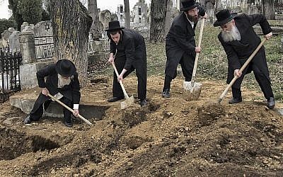 Les rabbins retrouvent les restes des victimes de la Shoah découverts dans une fosse commune au nord du cimetière juif de Iasi, en Roumanie, le lundi 4 avril 2011. Des membres de la communauté juive roumaine ont enterré les restes d'environ 60 Juifs tués par les troupes dans une fosse commune à Popricani, dans le nord de la Roumanie. (Crédit : AP / Radu Aneculaesi / Proimage)