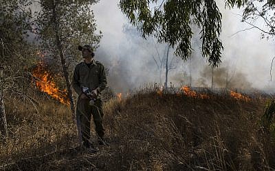Un soldat israélien combat un incendie déclenché par un engin incendiaire lancé depuis la bande de Gaza dans le sud d'Israël, le 26 juin 2019. (AP Photo/Tsafrir Abayov)