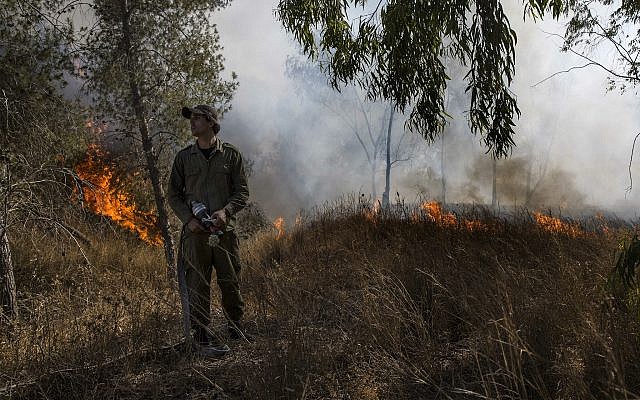 Un soldat israélien combat un incendie déclenché par un engin incendiaire lancé depuis la bande de Gaza dans le sud d'Israël, le 26 juin 2019. (AP Photo/Tsafrir Abayov)