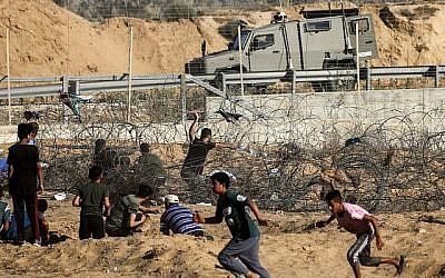 Un manifestant palestinien lance des pierres sur un véhicule de l'armée israélienne lors d'affrontements entre des manifestants palestiniens et des forces israéliennes à travers la barrière de fil barbelé au cours d'une manifestation à la frontière à proximité de Rafah dans le sud de la bande de Gaza, le 19 juillet 2019.
(SAID KHATIB / AFP) Un manifestant palestinien lance des pierres sur un véhicule de l'armée israélienne lors d'affrontements entre des manifestants palestiniens et des forces israéliennes à travers la barrière de fil barbelé au cours d'une manifestation à la frontière à proximité de Rafah dans le sud de la bande de Gaza, le 19 juillet 2019.
(SAID KHATIB / AFP)