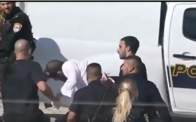 Un policier tire un manifestant haredi par les papillotes, lors d'une manifestation à Beit Shemesh, le 5 juillet 2019. (Capture d'écran Twitter)