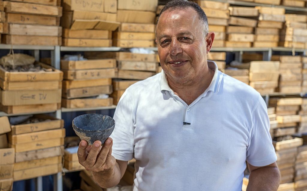 Le Dr Hamoudi Khalaily, directeur des fouilles de l'Autorité israélienne des Antiquités sur le site de Motza, avec en main un bol du Néolithique. (Yaniv Berman, Autorité israélienne des Antiquités)