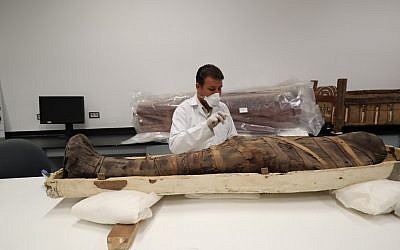 Un archéologue égyptien vérifie une momie durant un travail de restauration sur le sarcophage de Toutankhamon, au musée egyptie, le 4 août 2019. (Crédit : Khaled DESOUKI / AFP)