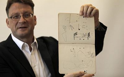 Le documentaliste de la Bibliothèque nationale d'Israël Stefan Litt montre des croquis de Franz Kafka, durant une conférence de presse le 7 août 2019. (Crédit :MENAHEM KAHANA / AFP)