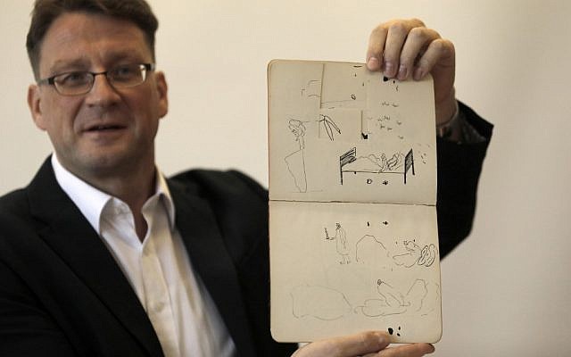 Le documentaliste de la Bibliothèque nationale d'Israël Stefan Litt montre des croquis de Franz Kafka, durant une conférence de presse le 7 août 2019. (Crédit :MENAHEM KAHANA / AFP)
