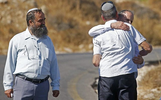 Des Israéliens se prennent dans les bras près de là où Dvir Sorek a été retrouvé poignardé à mort, près de l'implantation de Migdal Oz en Cisjordanie, le 8 août 2019. (Crédit : Hazem Bader/AFP) Des Israéliens se prennent dans les bras près de là où Dvir Sorek a été retrouvé poignardé à mort, près de l'implantation de Migdal Oz en Cisjordanie, le 8 août 2019. (Crédit : Hazem Bader/AFP)