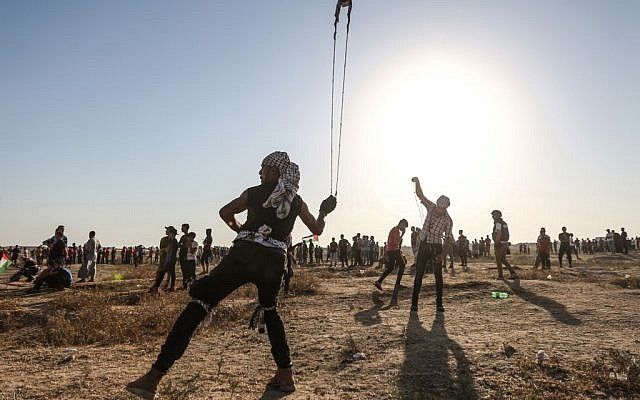 Un manifestant palestinien utilise une fronde pour jeter des pierres durant un affrontement au bord de la frontière avec Israël à l'est de la bande de Gaza, le 16 août 2019 (Crédit : MAHMUD HAMS / AFP) Un manifestant palestinien utilise une fronde pour jeter des pierres durant un affrontement au bord de la frontière avec Israël à l'est de la bande de Gaza, le 16 août 2019 (Crédit : MAHMUD HAMS / AFP)