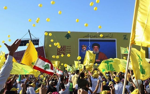 Les partisans du groupe terroriste du Hezbollah agitent le drapeau du groupe lors de la commémoration du 13e anniversaire de la fin de la guerre de 2006 avec Israël dans la ville de Bint Jbeil dans le sud du Liban, le 16 août 2019. (Crédit : Mahmoud ZAYYAT / AFP)