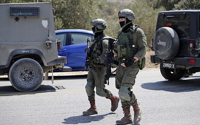 Des soldats israéliens sur le site de l'explosion d'une bombe, près de l'implantation de Dolev, en Cisjordanie, qui a tué une adolescente et blessé deux autres, le 23 août 2019 (Crédit : Ahmad GHARABLI / AFP)
