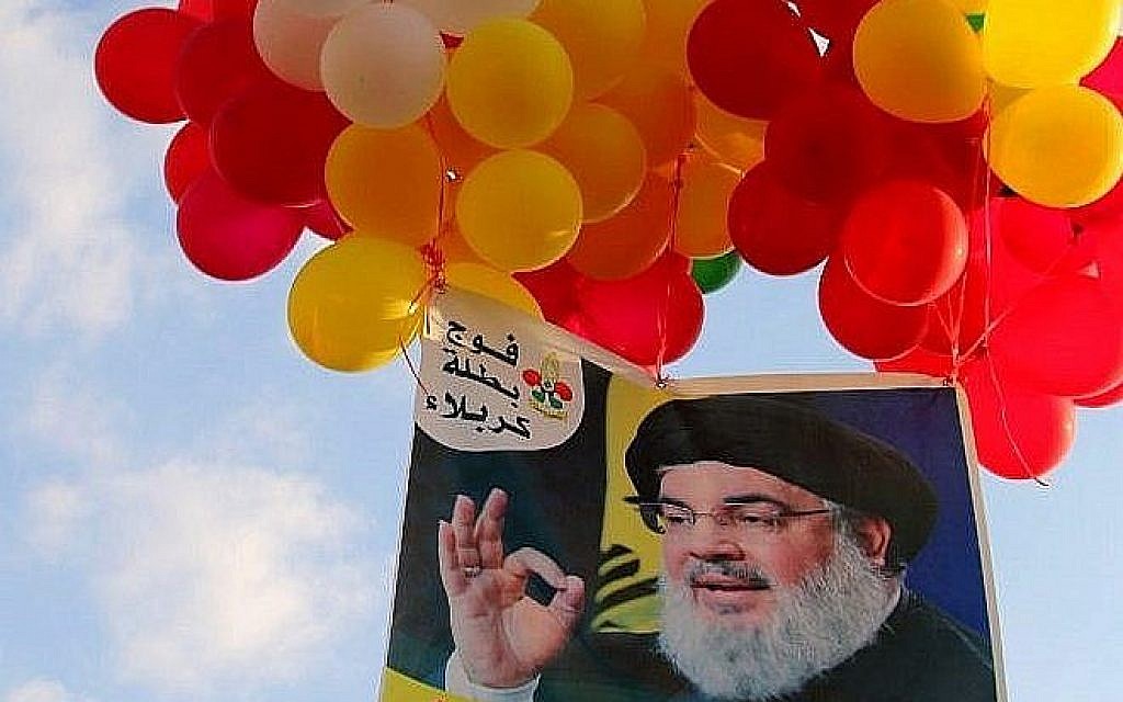 Une photographie du leader du mouvement libanais chiite du Hezbollah attachée à des ballons pendant un rassemblement du groupe terroriste dans la ville d'Al-Ain, dans la vallée du Bekaa, au Liban, le 25 août 2019 (Crédit : AFP)