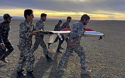 Sur cette photo fournie par l'armée iranienne, des soldats transportent les débris d'un drone durant des exercices à Semnan, en Iran (Crédit : Armée iranienne via AP)