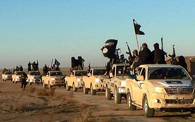 Dans cette photo non datée mise en ligne à l'été 2014, des terroristes du groupe de l'État islamique brandissent leurs armes et agitent des drapeaux à bord de leurs véhicules en route vers l'Irak, à Raqqa, en Syrie. (Photo militante via AP, File)