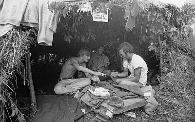 Des fans de musique sous une hutte en herbe au festival d'art et de musique de Woodstock, le 17 août 1969 (Crédit : AP Photo) Des fans de musique sous une hutte en herbe au festival d'art et de musique de Woodstock, le 17 août 1969 (Crédit : AP Photo)