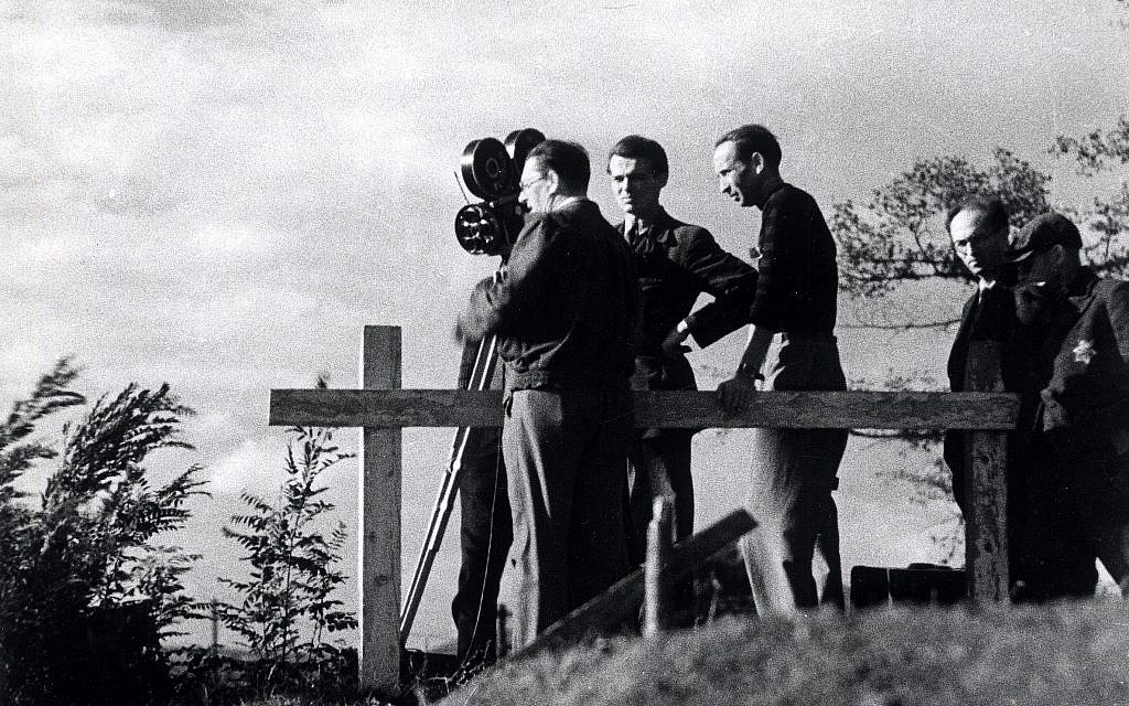 Une équipe de tournage réalise des prises de vue dans le ghetto de Theresienstadt lors du tournage d'un film de propagande nazie en 1944. Un assistant juif portant une étoile de David est à droite. (Domaine public)