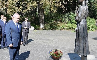 Le Premier ministre Benjamin Netanyahu dépose un panier d'épis de blé au monument dédié aux victimes de l'Holodomor, une famine créée intentionnellement ayant provoqué la mort de millions d'Ukrainiens et d'autres, à Kiev, le 19 août 2019. (Crédit : Amos Ben Gershom/GPO)