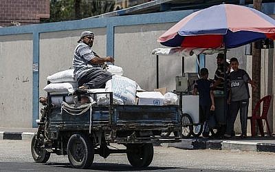 Un Palestinien se trouve sur un pickup transportant un sac d'aide alimentaire fourni par l'UNRWA au sud de Gaza ville à Rafah, le 25 juin 2019. (Said Khatib/AFP)