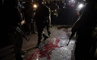Des hommes armés et masqués du Hamas montent la garde autour de taches de sang après une explosion qui a ciblé un barrage de police du Hamas à Gaza ville, le mardi 27 août 2019. (AP Photo/Khalil Hamra)