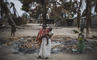 Une femme tient son enfant dans une région brûlée après une récente attaque du village d'Aldeia da Paz au Mozambique, le 24 août 2019. (Crédit : MARCO LONGARI / AFP)