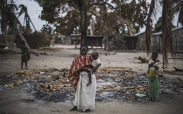 Une femme tient son enfant dans une région brûlée après une récente attaque du village d'Aldeia da Paz au Mozambique, le 24 août 2019. (Crédit : MARCO LONGARI / AFP)