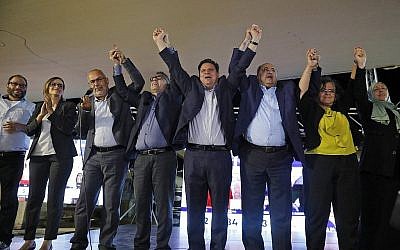 (G à D) Ofer Cassif, Heba Yazbak, Osama Saadi, Mtanes Shehadeh, Ayman Odeh, Ahmad Tibi, Aida Touma et Iman Khatib Yassin, devant leurs partisans au siège de campagne de la Liste arabe unie à Nazareth, dans le nord d'Israël, le 17 septembre 2019, à l'annonce des premiers sondages de sortie des urnes. (Crédit : Ahmad GHARABLI / AFP)