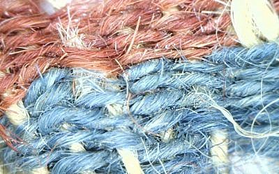 Des fragments de textile en laine séché avec des bandes rouges et bleues trouvées dans la vallée de Timna, en Israël (Crédit : Clara Amit, Autorisation : Autorité israélienne des antiquités)