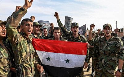 Les soldats du gouvernement syrien scandent des slogans lors d'une photo de groupe avec des portraits du président Bashar al-Assad près de Manbij, au nord de la province d'Alep, le 15 octobre 2019 (Crédit : - / AFP)