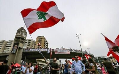 Un homme brandit un drapeau du Liban durant une manifestation sur l'autoroute qui relie Beyrouth à Tripoli, pendant des manifestations contre l'augmentation des impôts et la corruption au sein du gouvernement, le 26 octobre 2019. (Crédit : JOSEPH EID / AFP) Un homme brandit un drapeau du Liban durant une manifestation sur l'autoroute qui relie Beyrouth à Tripoli, pendant des manifestations contre l'augmentation des impôts et la corruption au sein du gouvernement, le 26 octobre 2019. (Crédit : JOSEPH EID / AFP)