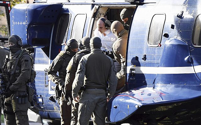 Le suspect de Halle, en combinaison blanche, escorté par la police, arrive au bureau du procureur de Karlsruhe, le 10 octobre 2019. (Crédit : Uli Deck/dpa via AP)