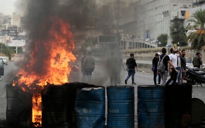 Des manifestants anti-gouvernements incendient des pneus pour bloquer une autoroute qui relie Beyriuth au nord du Liban à Zouk Mosbeh, le 28 octobre 2019. (Crédit : AP Photo/Hassan Ammar)