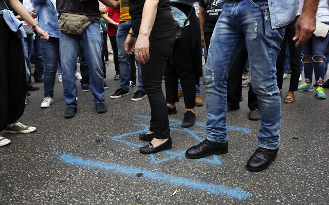 Des manifestant piétinent une Etoile de Daviid durant des manifestations contre le gouvernement libanais, à Beyrouth, le 28 octobre 2019. (Crédit : AP Photo/Bilal Hussein) Des manifestant piétinent une Etoile de Daviid durant des manifestations contre le gouvernement libanais, à Beyrouth, le 28 octobre 2019. (Crédit : AP Photo/Bilal Hussein)