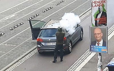 Un homme armé tire dans une rue de Halle, en Allemagne, après une fusillade devant une synagogue dans la même ville, faisant deux morts. (Crédit : capture d'écran / Andreas Splett / ATV-Studio Halle / AFP)