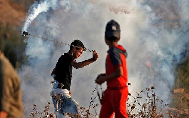 Un manifestant palestinien utilise une fronde pour renvoyer des bonbonnes de gaz lacrymogène sur les soldats israéliens pendant des affrontements lors de manifestations à la frontière avec Israël à l'est de Bureji dans le centre de la bande de Gaza, le 18 octobre 2019. (Photo de MAHMUD HAMS / AFP) Un manifestant palestinien utilise une fronde pour renvoyer des bonbonnes de gaz lacrymogène sur les soldats israéliens pendant des affrontements lors de manifestations à la frontière avec Israël à l'est de Bureji dans le centre de la bande de Gaza, le 18 octobre 2019. (Photo de MAHMUD HAMS / AFP)