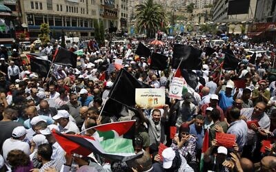 Des manifestants palestiniens brandissent des banderoles et des drapeaux nationaux lors d'une manifestation contre la conférence économique du Moyen Orient parrainée par les États-Unis qui s'est ouverte à Bahreïn, dans la ville de Naplouse, en Cisjordanie, le 25 juin 2019. (Jaafar Ashtiyeh/AFP)