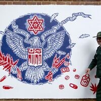 Un membre des gardiens de la Révolution de l'Iran passe devant une peinture murale peinte sur les murs de l'ancienne ambassade américaine dans la capitale de Téhéran, le 2 novembre 2019. (Photo par ATTA KENARE / AFP)