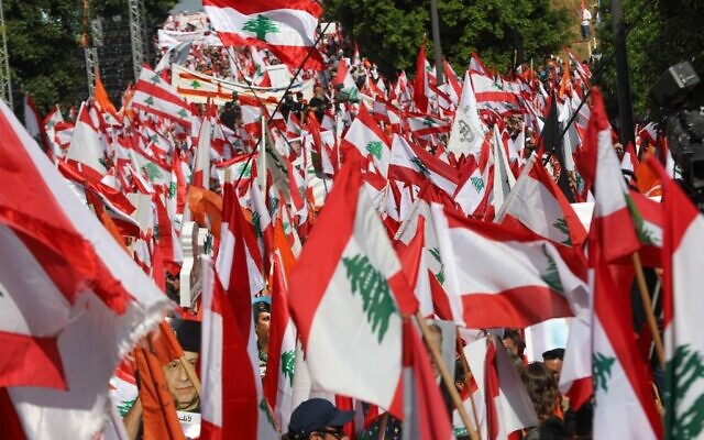 Des partisans du président libanais Michel Aoun agitent des drapeaux nationaux et des bannières de couleur orange du parti politique qu'il a fondé (Le Mouvement patriotique libre) lors d'une contre manifestation à proximité du palais présidentiel à Baabda le 3 novembre 2019.(Photo by Anwar AMRO / AFP)