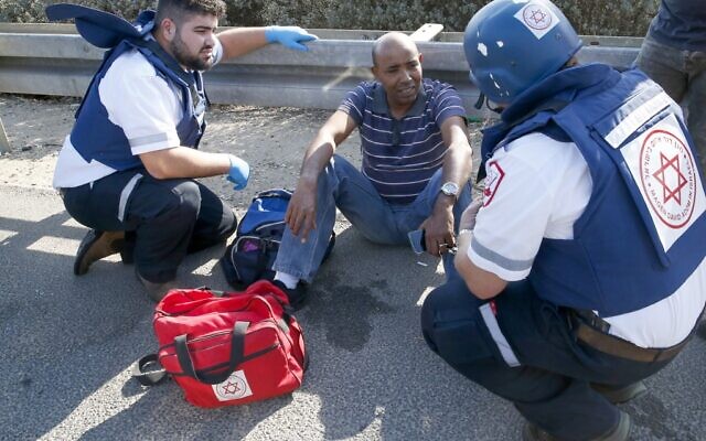 Des secouristes israéliens soignent un homme blessé sur une autoroute, à Ashdod, le 12 novembre 2019. (Crédit : JACK GUEZ / AFP)