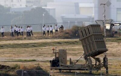 Des étudiants israéliens marchent devant une batterie du système de défense antimissiles du Dôme de fer, chargé d'intercepter et de détruire les roquettes à courte-portée et les obus d'artillerie dans la ville d'Ashdod, dans le sud d'Israël, près de la bande de Gaza, le 12 novembre 2019 (Crédit : JACK GUEZ / AFP) Des étudiants israéliens marchent devant une batterie du système de défense antimissiles du Dôme de fer, chargé d'intercepter et de détruire les roquettes à courte-portée et les obus d'artillerie dans la ville d'Ashdod, dans le sud d'Israël, près de la bande de Gaza, le 12 novembre 2019 (Crédit : JACK GUEZ / AFP)