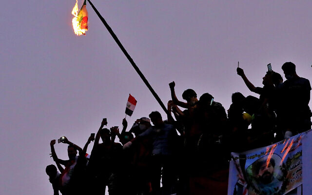Des manifestants anti-gouvernementaux irakiens brûlent le drapeau iranien lors d'une manifestation à Bagdad, en Irak, le mardi 29 octobre 2019. (Crédit : AP / Hadi Mizban) Des manifestants anti-gouvernementaux irakiens brûlent le drapeau iranien lors d'une manifestation à Bagdad, en Irak, le mardi 29 octobre 2019. (Crédit : AP / Hadi Mizban)