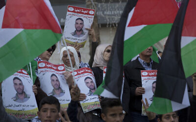 Des manifestants agitent des panneaux à l'effigie de Sami Abu Diak, un terroriste palestinien décédé d'un cancer dans les prisons israéliennes, durant une manifestation à Ramallah, le 26 novembre 2019. (Crédit : AP Photo/Nasser Nasser)