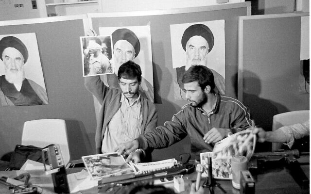 Un représentant des étudiants iraniens tient un portrait de l'un des otages, les yeux bandés, durant une conférence de presse à l'ambassade américaine de Téhéran, le 5 novembre 1979. (Crédit : AP)
