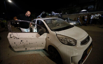 Un homme regarde une voiture endommagée par un éclat d'obus issu d'une roquette tirée de Gaza à Sdérot, en Israël, le 1er novembre 2019 (Crédit : AP Photo/Tsafrir Abayov)